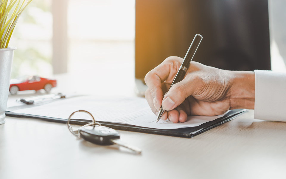 Hand writing information onto a contract with keys in foreground