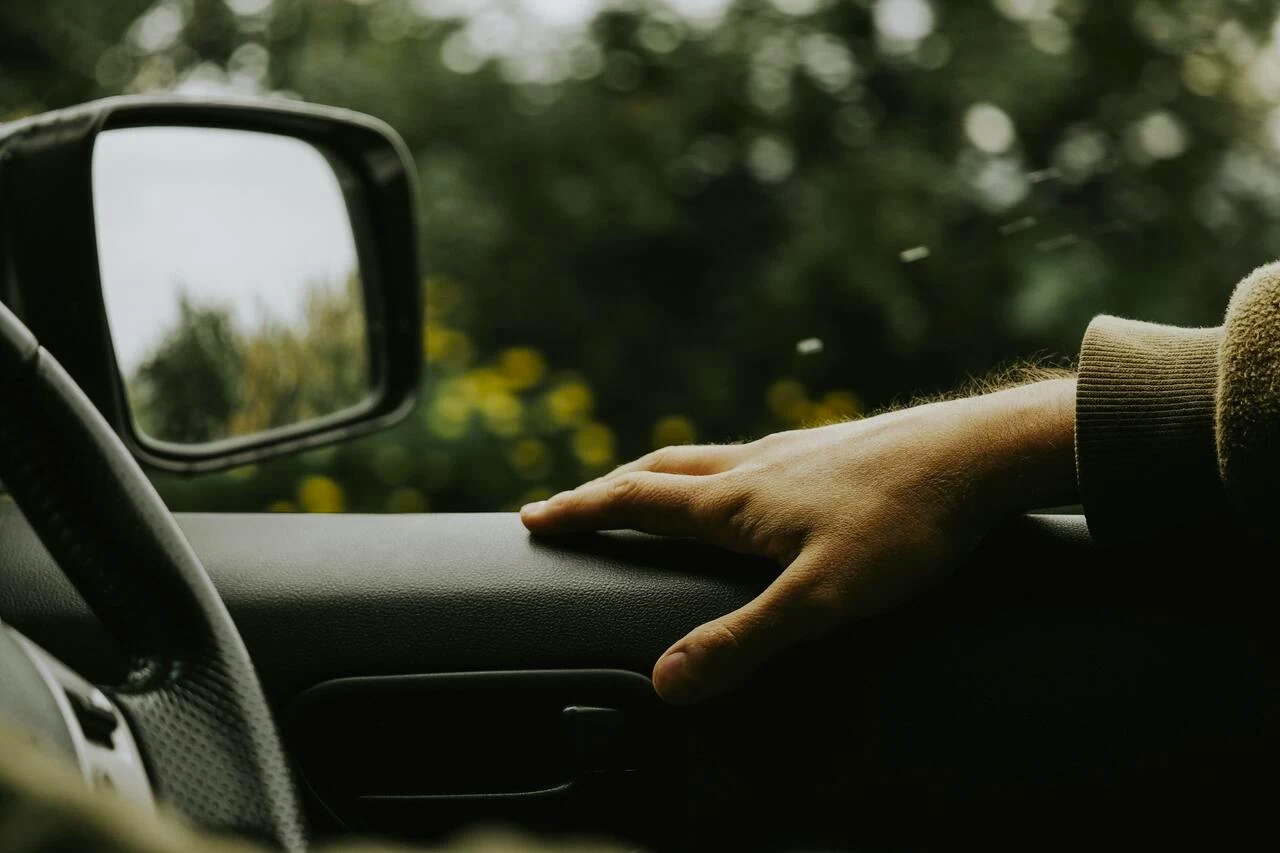 Picture of a hand resting on the window ledge of a car